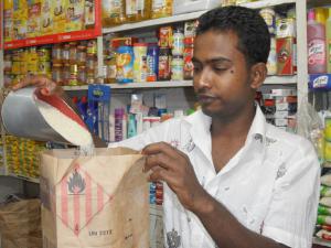 Lockdowns, shutdowns and other protection measures induced by the COVID-19-pandemic have disrupted the upstream (input supply and production), midstream (processing, marketing, and logistics), and downstream (retail and consumption) segments of the rice value chain A retailer measures rice into a bag at a retail outlet