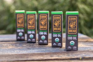 Five bottles of Cornbread Hemp's USDA certified organic Whole Flower CBD Oils in an organic hemp field.